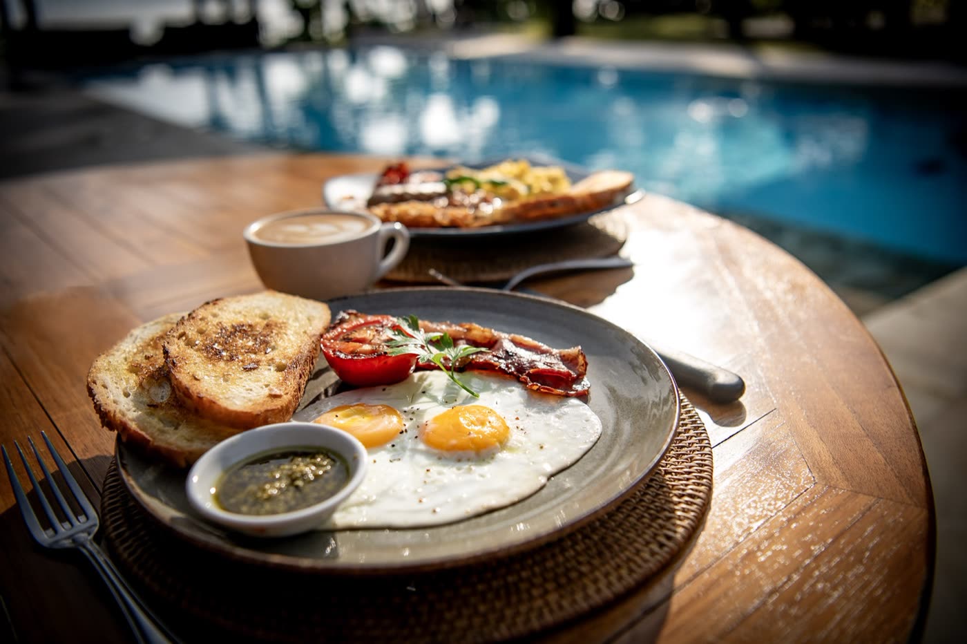 Breakfast of eggs, toast and coffee on a table beside the pool