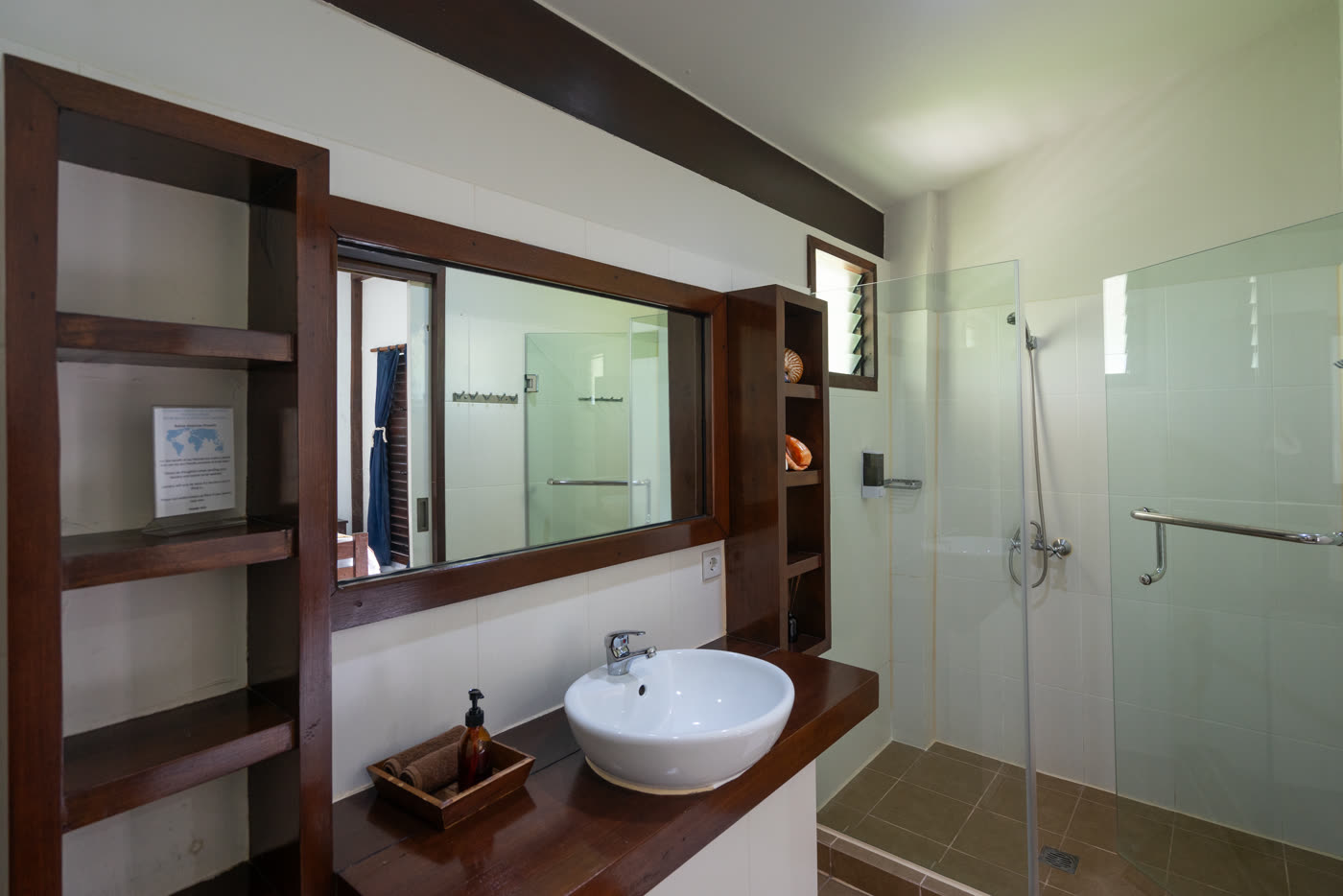 Resort bathroom with a glass shower and a wooden vanity