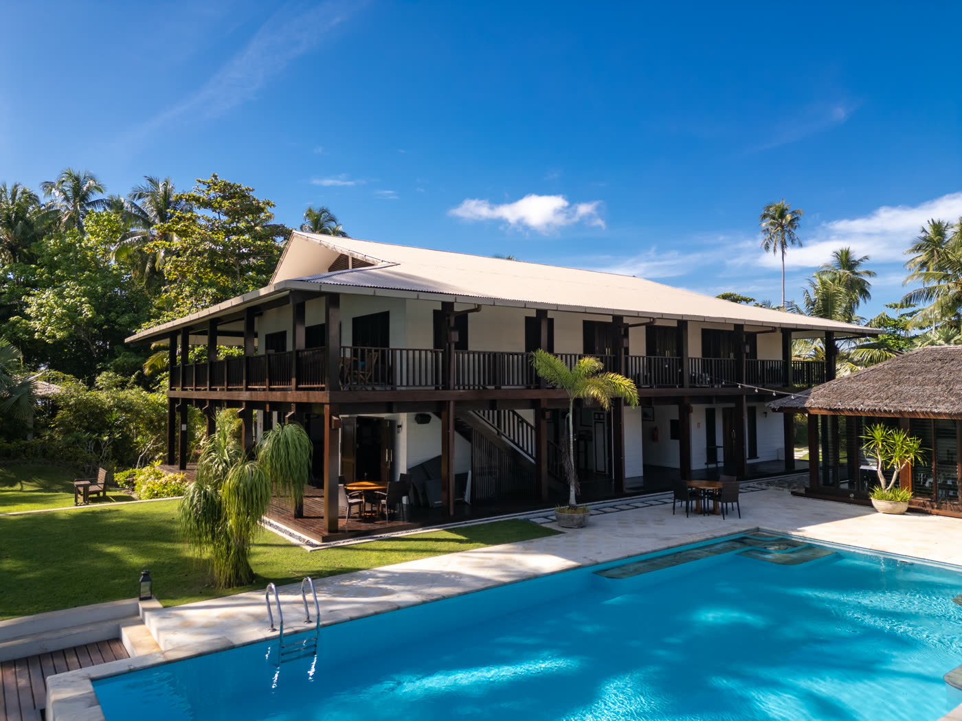 The two-storey resort building among palm trees, with the pool in front