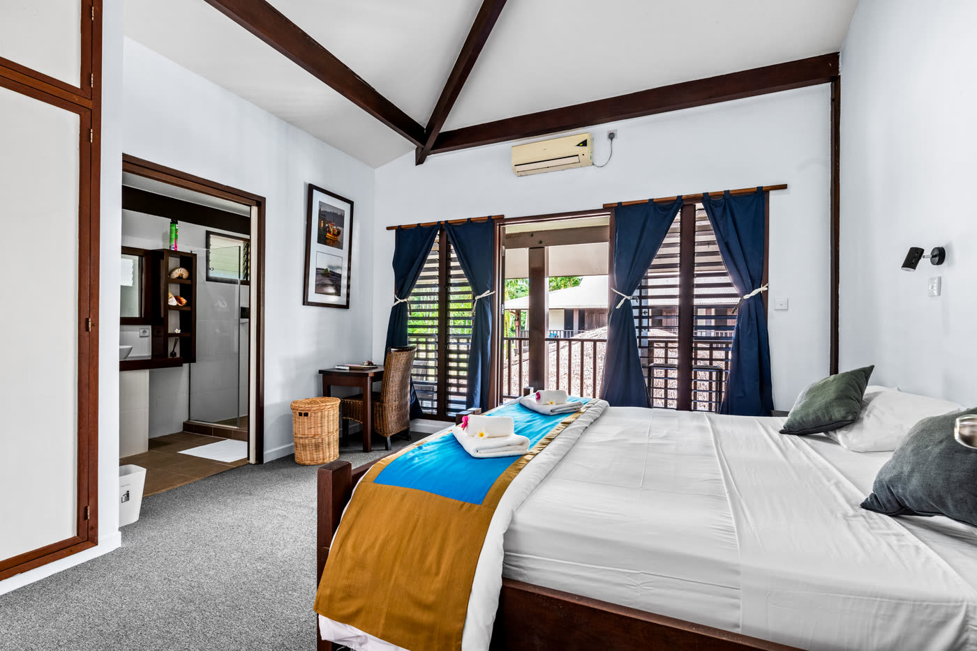A bright resort room with a large bed, air conditioning and doors to a balcony